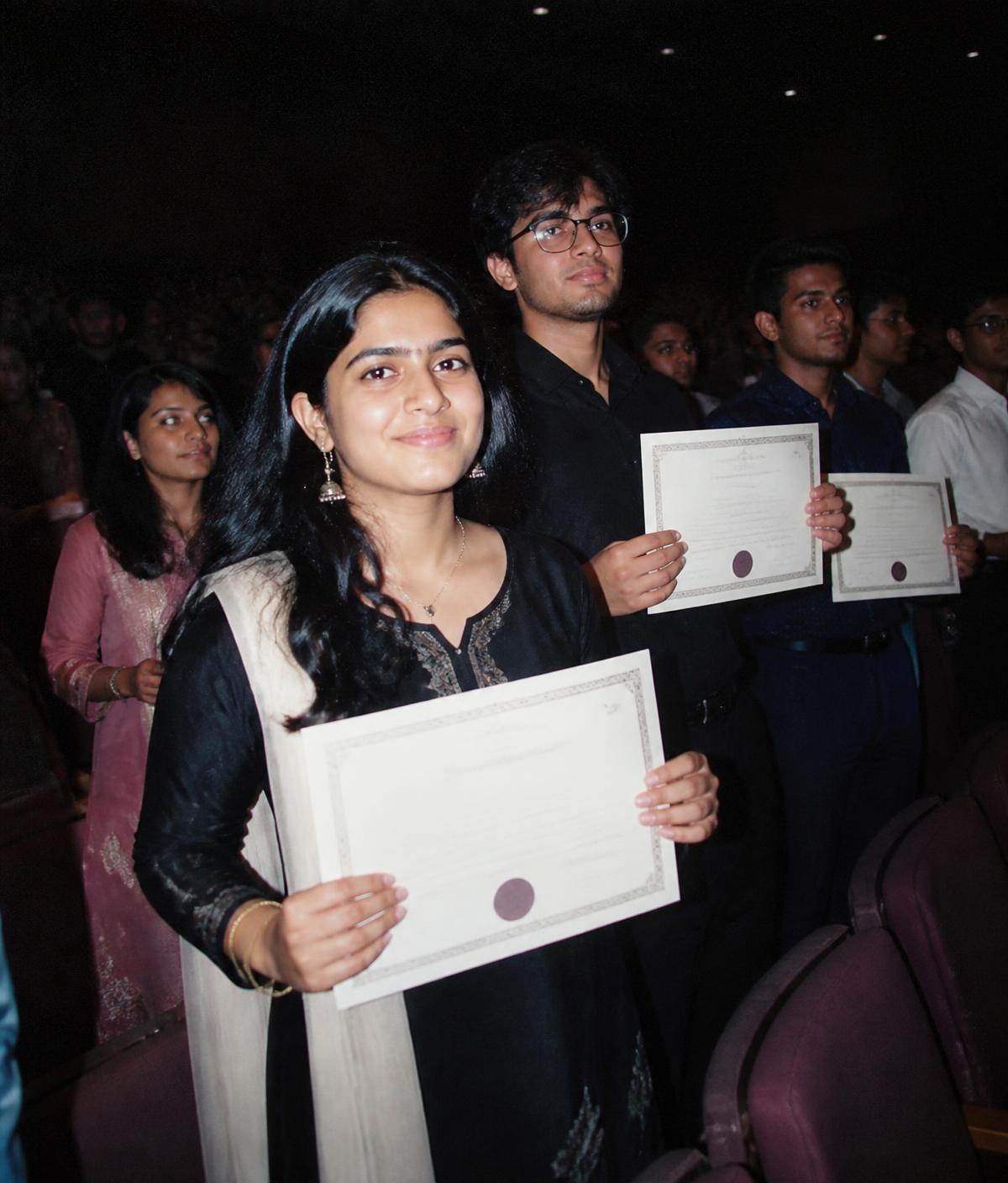 Students holding printed certificates after an event